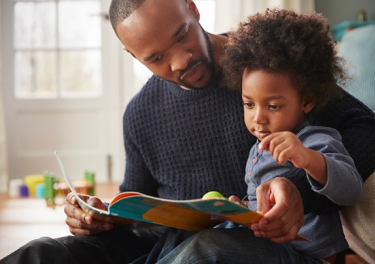 Padre Afroamericano leyendo con su hijo.